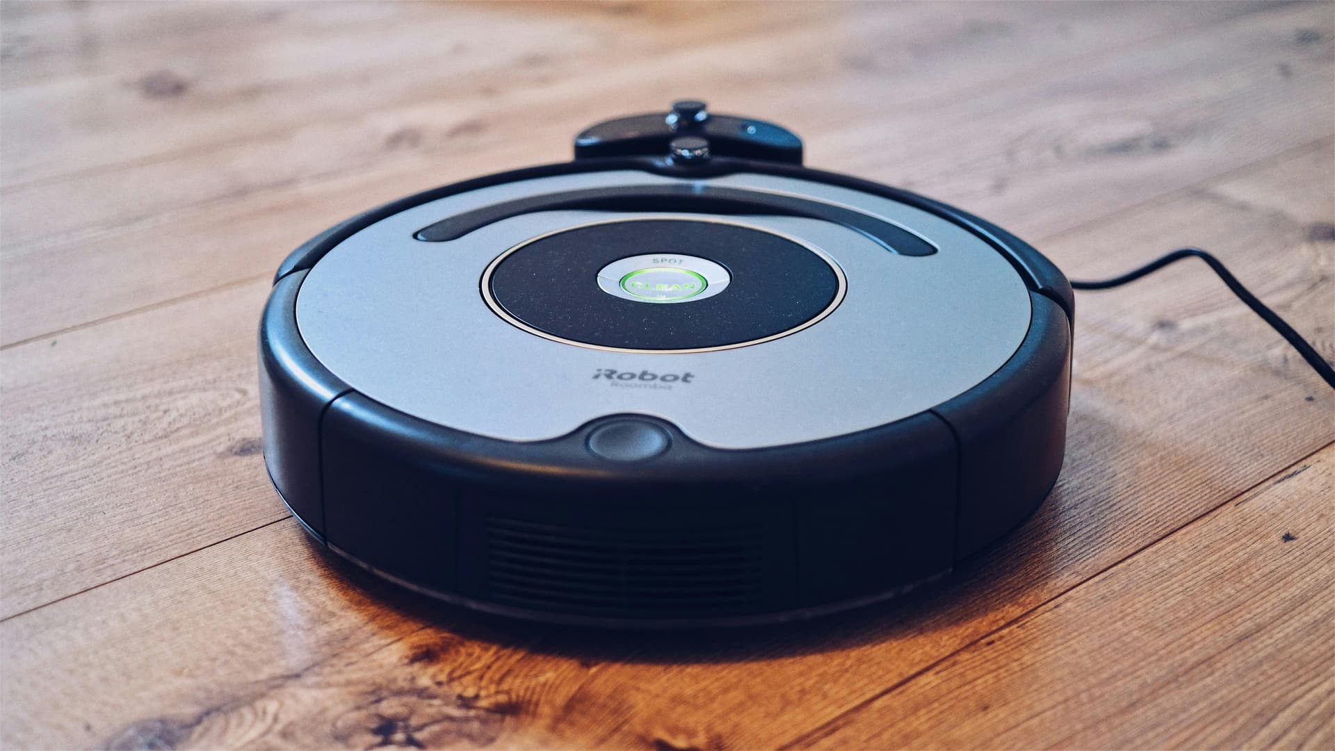 Robot vacuum cleaner on floor with person relaxing on sofa
