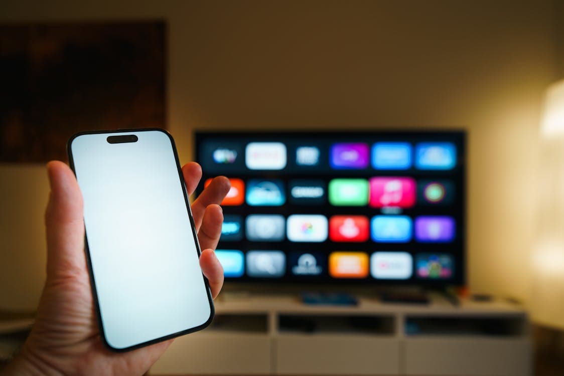 Smartphone controlling smart TV with streaming app icons